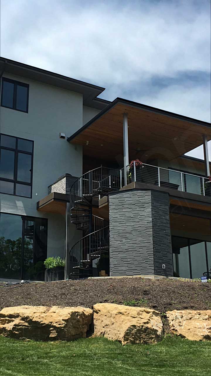 Rear elevation view of modern styled home outside of Kansas with grey basalt 3d ledge stone accents