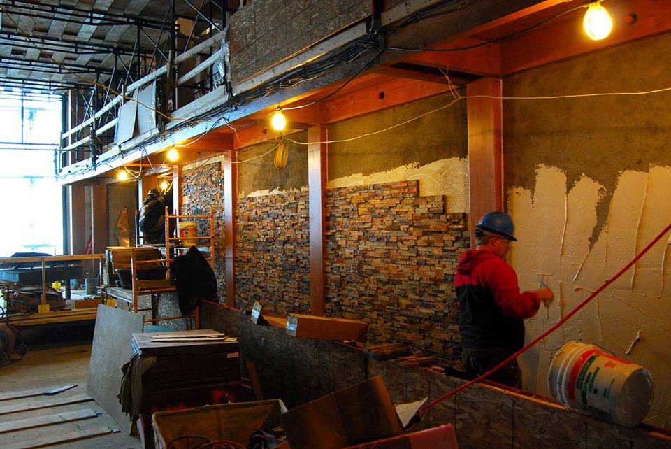 Stone masons installing stone veneer panels during the build phase of a construction project