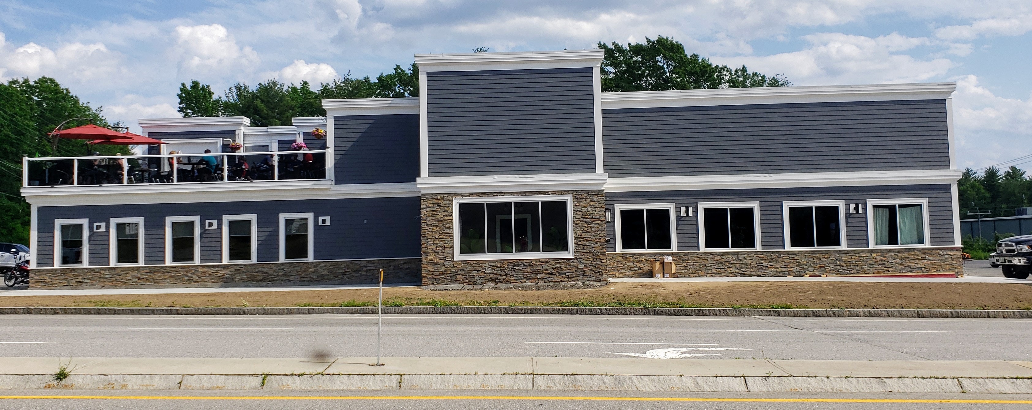 Remodeled Crow's Nest pub exterior facade with Norstone Ochre XL Stacked Stone Panels being installed as a wainscoat